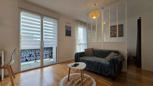 Modern apartment living room with balcony, sofa, round table, and wooden floors in La Fôret-Fouesnant