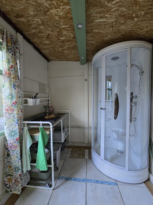 Cabine de douche moderne dans la salle de bains du gîte Domaine Trianon, Villandry avec lavabo et rideau fleuri