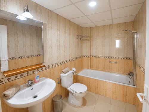 Baño moderno con paredes de azulejos beige, lavabo blanco, inodoro y bañera en Apartamentos El Calón Playa, Cuevas del Almanzora