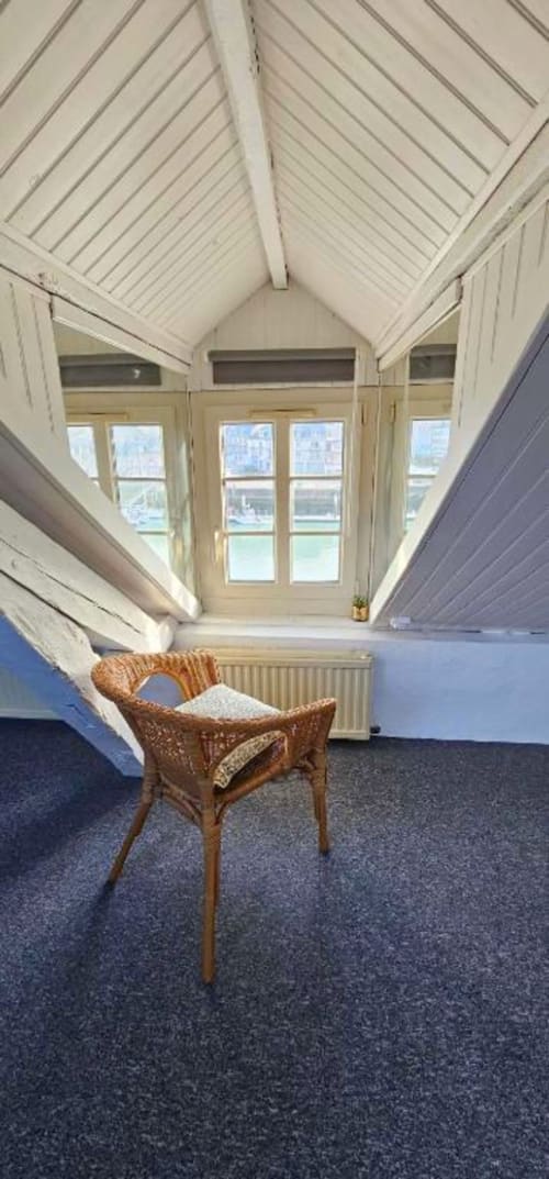 Intérieur lumineux d'un duplex d'atelier avec plafond voûté, chaise en bois et vues sur la mer à Saint-Valery-en-Caux