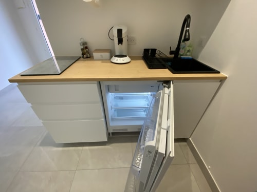 Compact kitchenette with refrigerator, coffee maker, and countertop appliances at La Maison Blanche apartment in Bouguenais