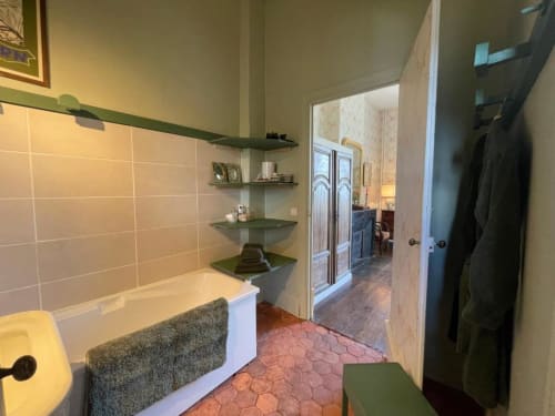 Salle de bain avec murs carrelés, baignoire profonde et étagères d'angle au Château de Vaux Morvan à Étang sur Arroux