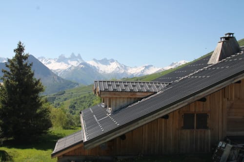Chalet La Louvière with snow-capped Alps, wooden architecture, metal roofing, green valley in La Toussuire