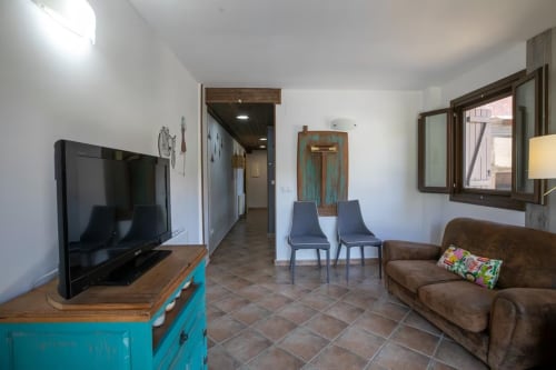 Moderno salón en Montgat con sofá marrón, televisor, consola turquesa, comedor, vistas a la montaña y tonos de terracota