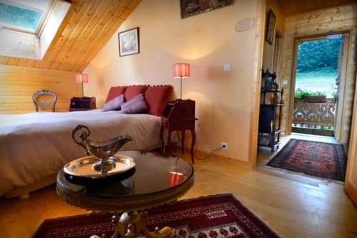 Chambre Méridien à l'Auberge Nemoz : poutres en bois, coussins rouges, terrasse vue montagne, décor traditionnel