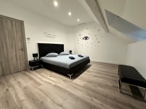 Chambre moderne avec lit noir, parquet en bois et art mural au Gîte Les Camélias 71, Oslon, France