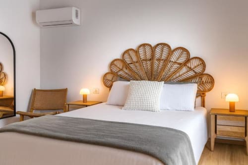 Dormitorio moderno en Rural La Palma con cabecera de pavo real tejido, ropa de cama blanca y mesitas de noche de madera con lámparas.