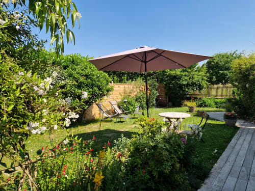 Terrasse verdoyante aux Chambres du Keriolet à La Trinité sur Mer avec parasol, chaises longues et plantes fleuries
