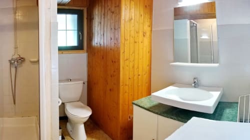 Modern bathroom at Chalet La Louvière with white sink, toilet, shower, and wooden accents in La Toussuire