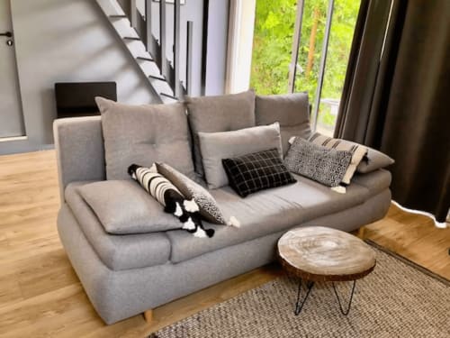 Canapé gris rembourré avec coussins décor et table d'appoint en bois dans le salon du loft cottage ART DE VOYAGER.