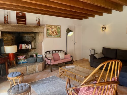 Salon chaleureux du Château de Vaux Morvan avec cheminée, fauteuils en rotin et vue sur le jardin