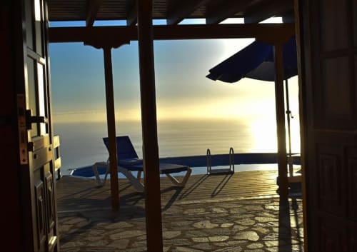 Terraza con vista al océano en Villa Las Flores, La Palma, con tumbonas, sombrilla y puesta de sol sobre el mar