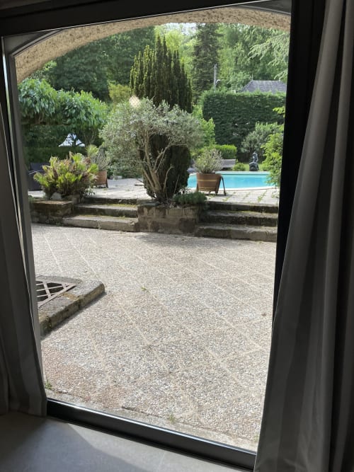 Vue depuis le cottage Le Loft aux Chambres d'hôtes Les Pratges à Figeac : piscine, jardin avec oliviers et ambiance méditerranéenne