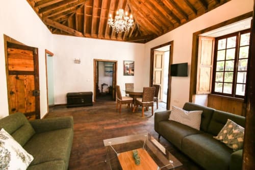 Amplio salón en Casa 1820, apartamento rural en Santa Cruz de la Palma, con vigas de madera, sofás, comedor y jardín