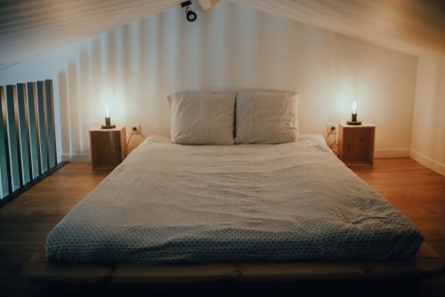 Chambre loft moderne à ART DE VOYAGER à Étretat avec lit queen-size, tables de nuit en bois, éclairage ambiant et plafond mansardé