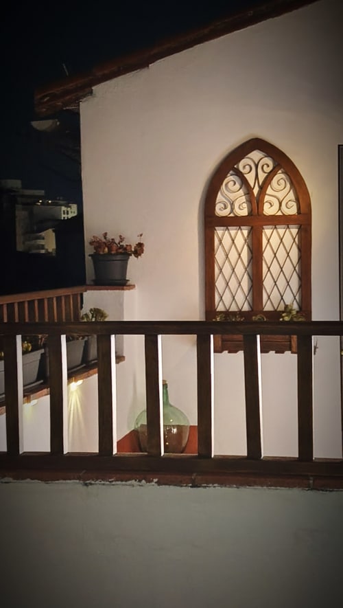 Ventana de arco medieval con cristalería decorativa en apartamento histórico de Cáceres, hotel Mirador Medieval