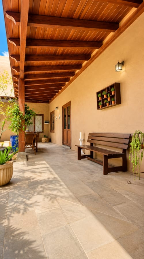 Patio couvert avec poutres en bois, murs en terre cuite, banc rustique, plantes en pot et carrelage à Casa Miranda, Corralejo