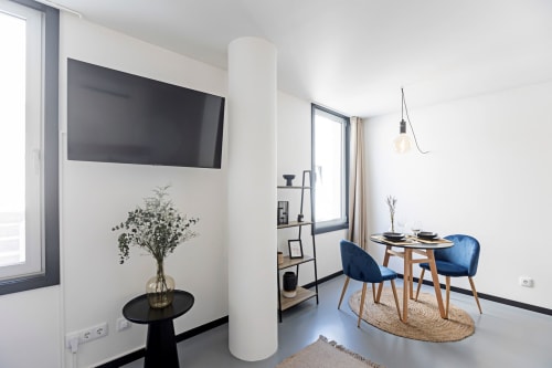Moderno apartamento estúdio no Porto com TV tela plana, área de refeições com cadeiras azuis, kitchenette e vista para a cidade