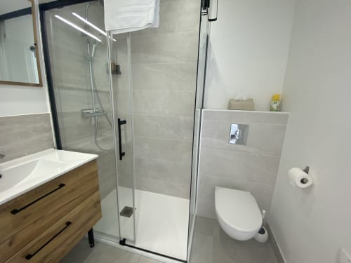Modern bathroom at La Maison Blanche in Bouguenais with walk-in shower, toilet, and wooden vanity