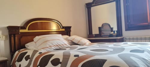 Dormitorio en el apartamento La Viña 2 de Casas Rurales con cabecero de madera, ropa de cama estampada y espejo