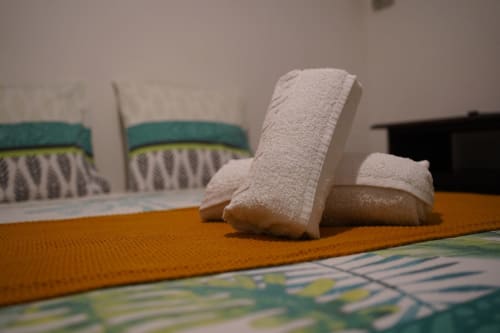 Serviettes roulées sur un tapis orange dans une chambre moderne de l'appartement Maisons En Or, Cayenne