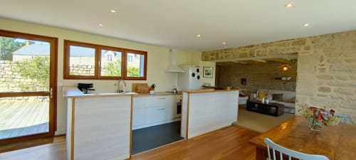 Cuisine et coin repas contemporains de la villa La Trinité avec mobilier blanc, poutres en bois, vue jardin par portes-fenêtres