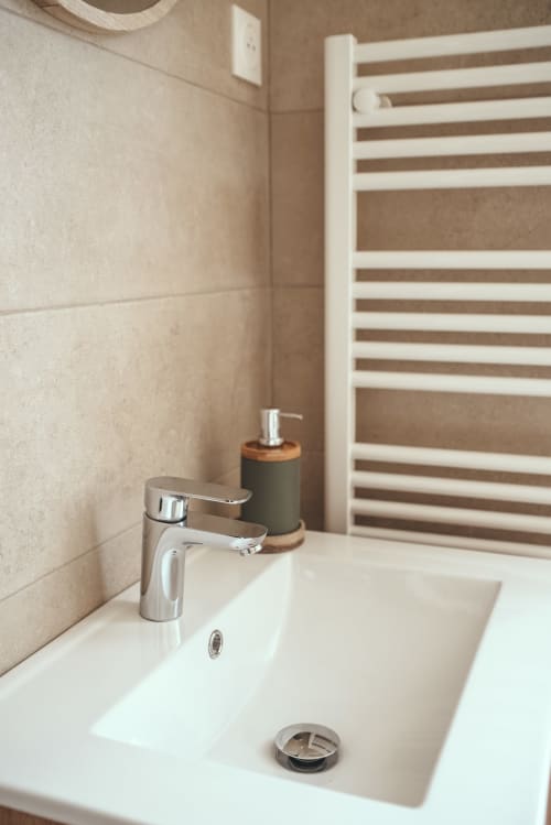 Lavabo moderne avec robinet chromé et distributeur de savon dans le cottage Les Tropiques à ART DE VOYAGER, Étretat