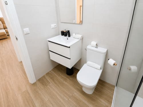 Modern bathroom with white vanity, toilet, and tiled walls in Apartamento Frontal Coral, Cuevas del Almanzora