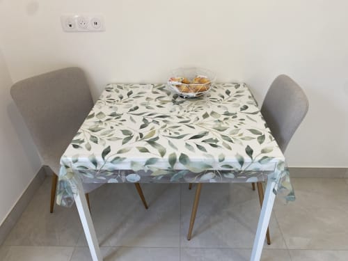 Table à manger avec nappe à motif feuillage, deux chaises grises et coupe de fruits dans l'appartement La Maison Blanche, Bouguenais