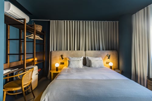 Estúdio Modern Standard na Benefit Collection Porto com cama queen, detalhes amarelos, beliches e paredes azul-petróleo escuro