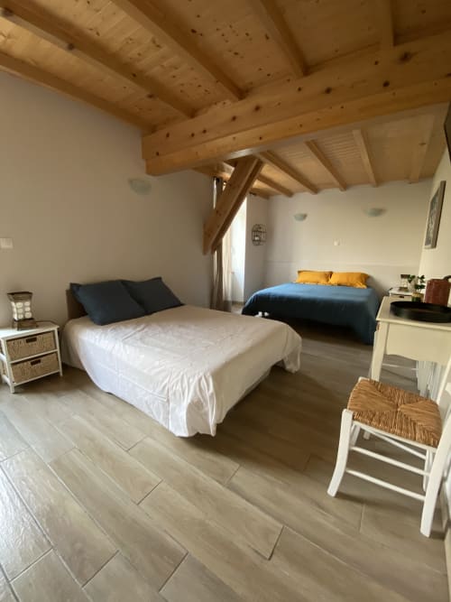 Chambre spacieuse au Le Cocon De Curson B&B à Chanos-Curson avec deux lits, poutres en bois apparent et parquet clair.