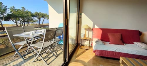 Balcon lumineux de Mer et Maisons avec vue sur la mer, coin repas et lit rouge visible à travers les portes vitrées