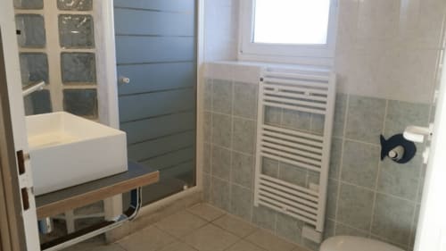 Salle de bains moderne de la villa Mer et Maisons à La Trinité sur Mer avec lavabo blanc, sèche-serviettes chauffant et douche carrelée