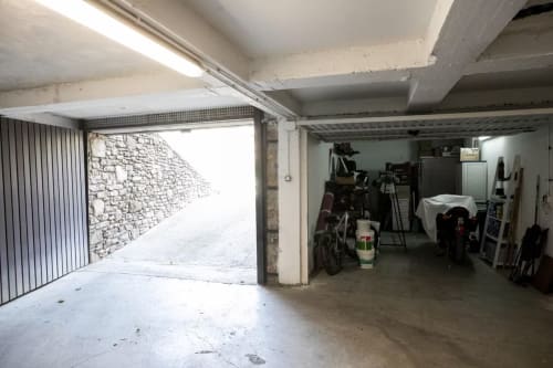 Interior de garaje con puerta abierta, motocicletas y artículos de almacenamiento en Front Beach Apartments, Montgat