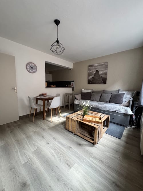 Studio moderne à Troyes avec séjour, canapé, table basse en bois, table à manger, coin cuisine et décor géométrique