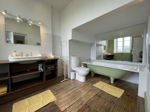 Salle de bain spacieuse au Château de Vaux Morvan avec vasques doubles, baignoire vintage verte et parquet à Étang sur Arroux
