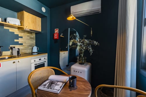 Studio compacto no Porto com kitchenette, paredes em azul-petróleo, mesa de madeira, refrigerador SMEG e comodidades modernas.