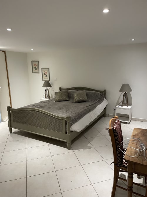 Chambre spacieuse du gîte Les Pratges à Figeac avec lit queen-size, tables de nuit assorties avec lampes, carrelage blanc et