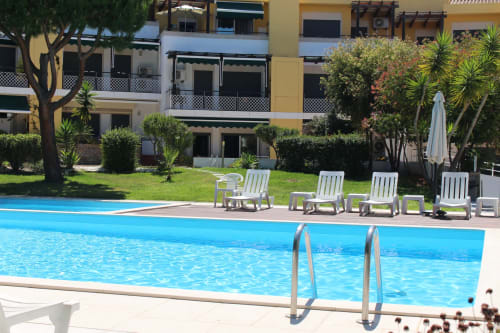 Break Lovers pool area in Tavira with blue swimming pool, white lounge chairs, and palm trees