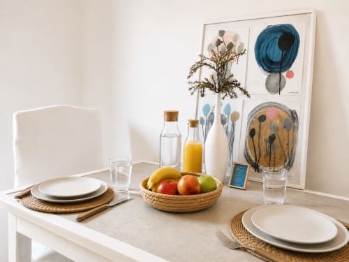 Élégante table de salle à manger chez Sara & Gino Fuerteventura avec couverts raffinés, corbeille de fruits frais et œuvre d'art contemporaine