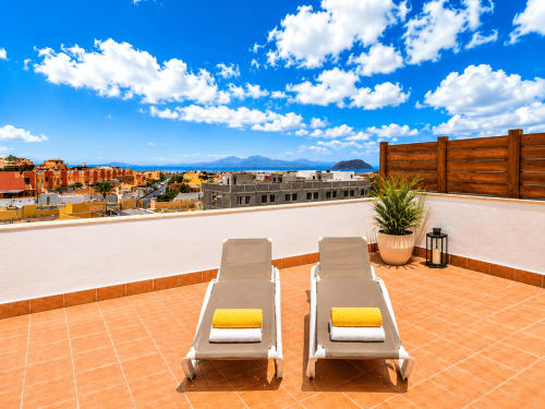 Deux transats avec serviettes sur une terrasse panoramique dominant Corralejo, Fuerteventura avec vue sur l'océan et les montagnes