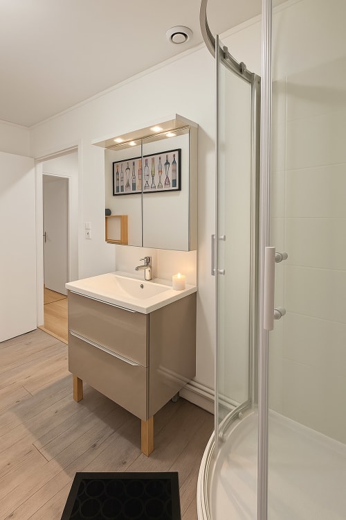 Salle de bain moderne avec lavabo, miroir et cabine de douche aux Gîtes Saint Valery En Caux