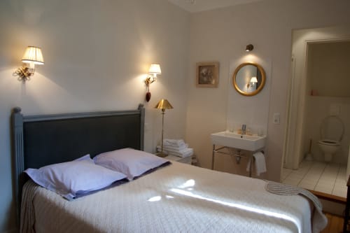 Chambre lumineuse aux Chambres d'hôtes Les Pratges à Figeac avec lit, appliques murales, lavabo attenant et miroir