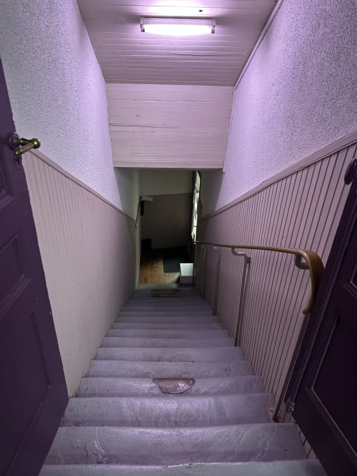 Escalier étroit aux murs violets et marches en bois à l'Hébergement Luxeuil Les Bains, Luxeuil-les-Bains