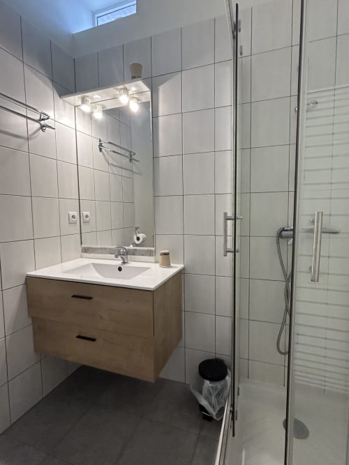 Salle de bains moderne de l'hôtel BDM à Montastruc-la-Conseillère avec meuble vasque en bois, carrelage blanc et douche à l'italienne