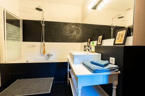 Salle de bains moderne au Mas F B&B à Saint-Rémy-de-Provence avec meuble vasque bleu, carrelage noir et blanc, et douche à effet pluie