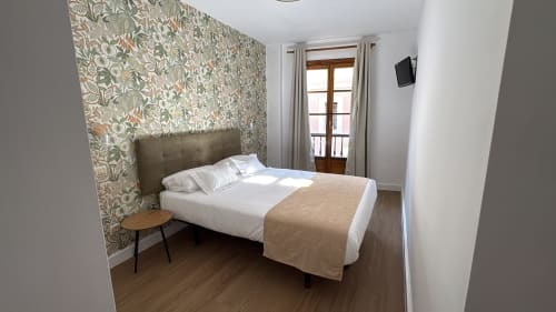 Moderna habitación doble en Pensión Argüelles de Ribadesella con papel pintado estampado, balcón con vistas a la ciudad y TV de pantalla plana