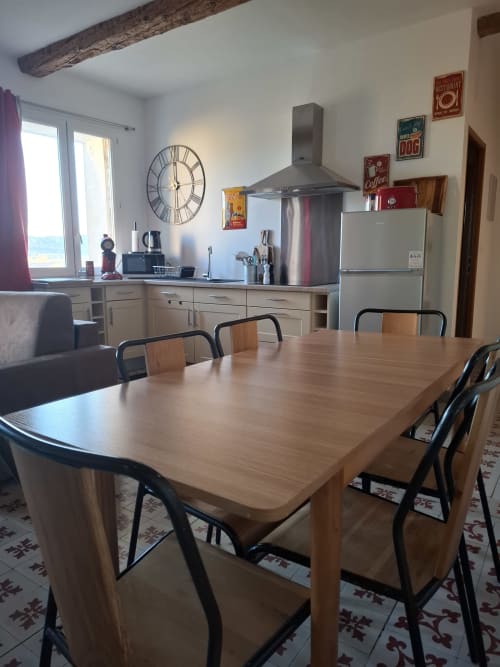 Spacieuse salle à manger de l'appartement Chez Laure & Marc avec table en bois, cuisine moderne et vue sur le jardin à Plaissan, France