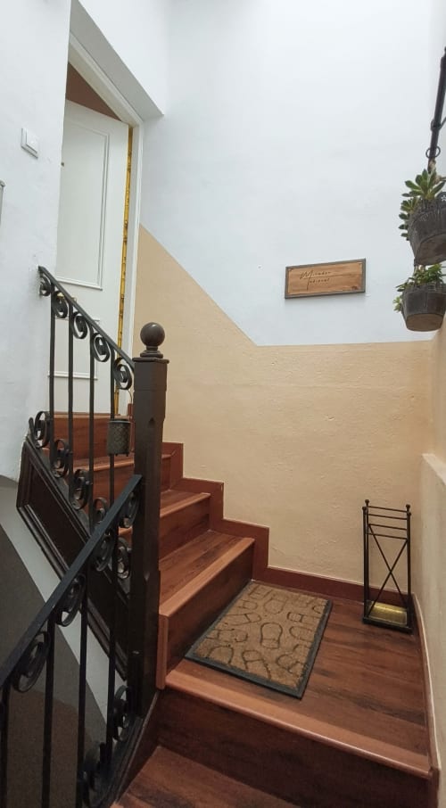 Escalera de entrada al apartamento Mirador Medieval en Cáceres con barandilla ornamentada y peldaños de terracota