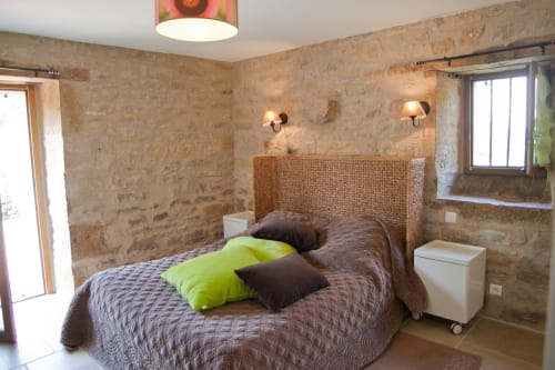 Chambre rustique en pierre aux Chambres d'hôtes Les Pratges à Figeac, tête de lit en osier et coussins vert anis